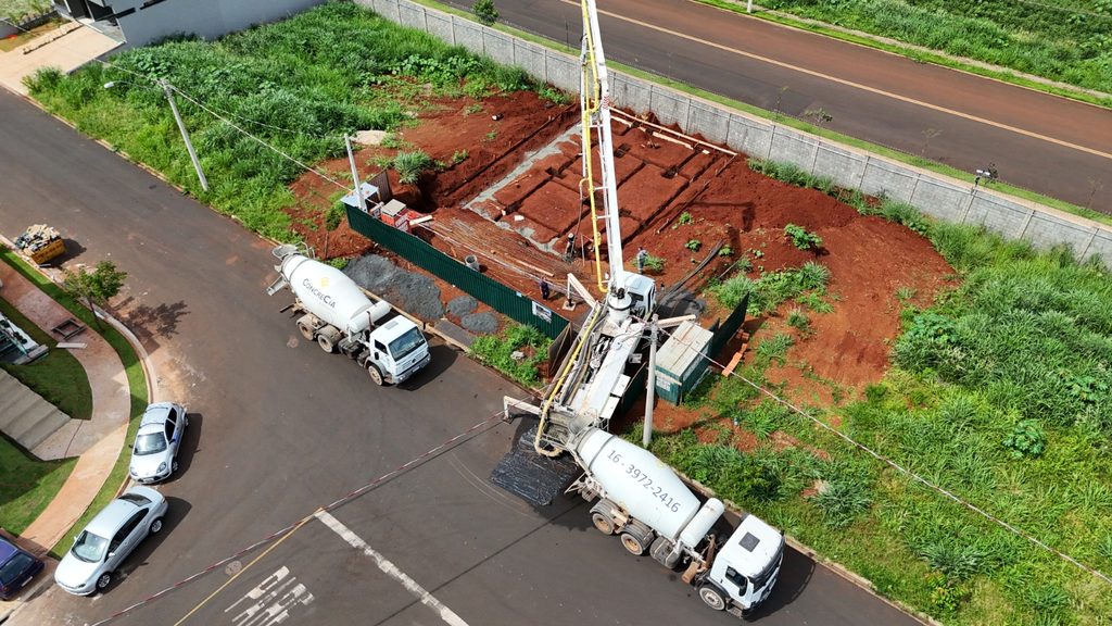 Vista aérea da bomba-lança e do caminhão betoneira da CONCRECIA concretando a fundação de uma casa